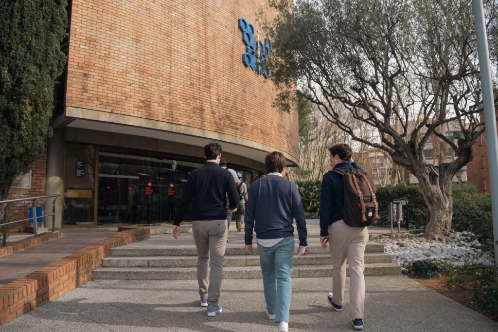 Three students approach a university building entrance