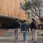 Three students approach a university building entrance