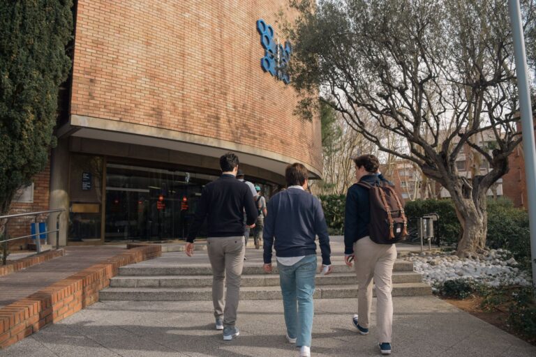 Three students approach a university building entrance